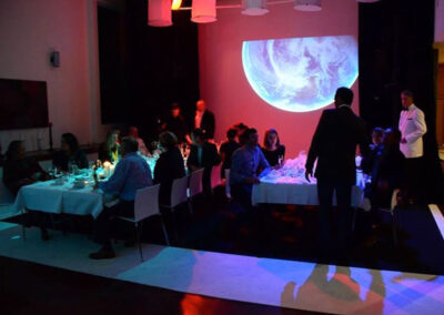 A large group seated at tables, enjoying dinner with soft lighting