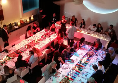 A large group of people enjoying dinner together at beautifully lit tables