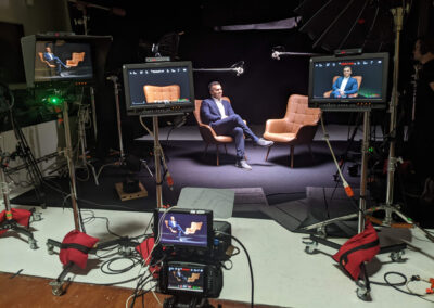 Podcast setup in a black limbo studio with microphones and lighting.